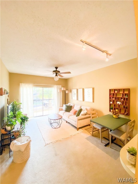 living room with a textured ceiling, ceiling fan, carpet flooring, and rail lighting