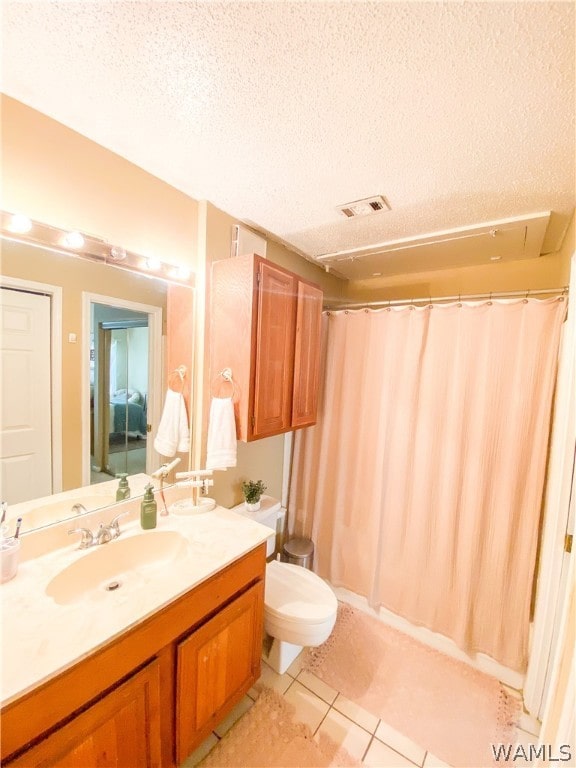 bathroom featuring vanity, a textured ceiling, tile patterned floors, and toilet