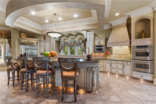 kitchen with a center island, a tray ceiling, appliances with stainless steel finishes, and cream cabinets