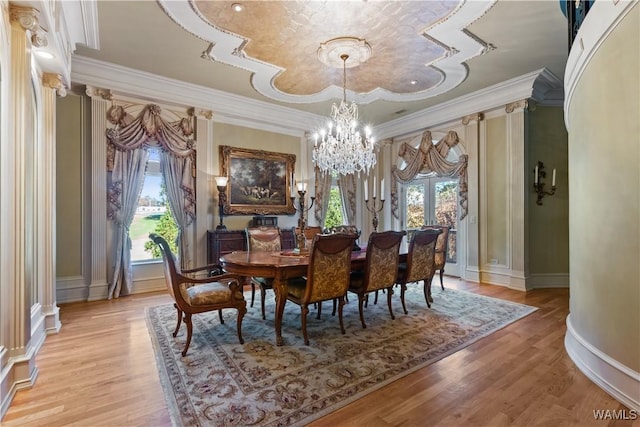 dining space with light wood-type flooring, ornamental molding, and a chandelier