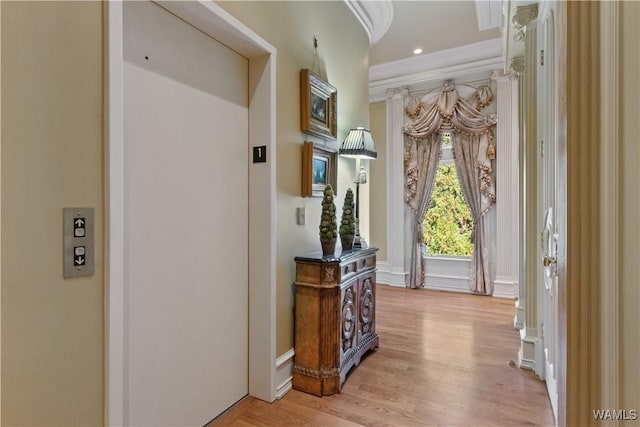 interior space featuring elevator, ornamental molding, and light wood-type flooring