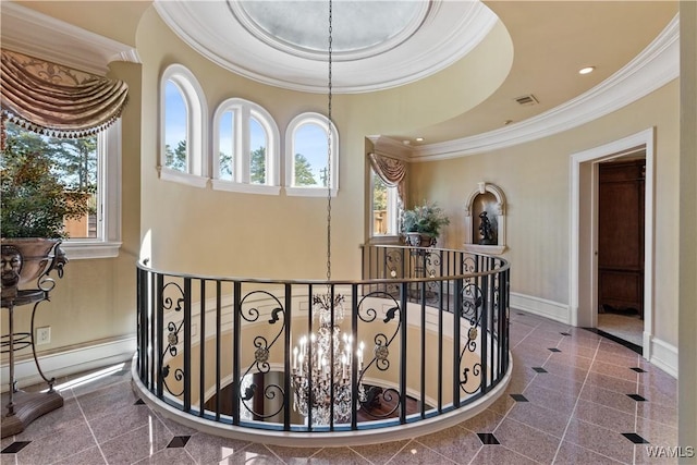 corridor featuring a notable chandelier, a raised ceiling, and ornamental molding