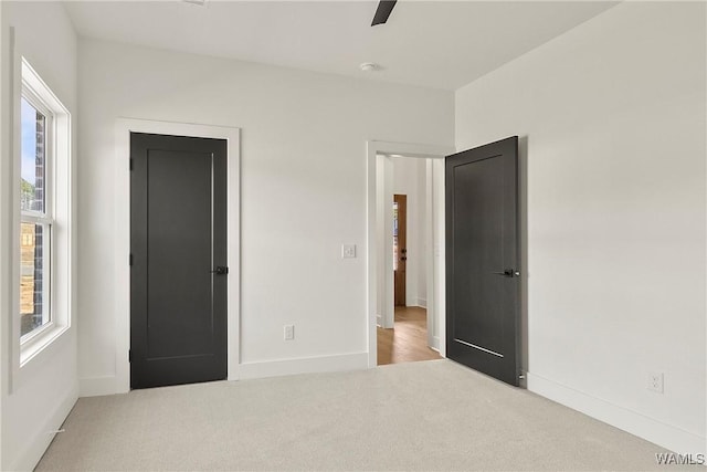 unfurnished bedroom with ceiling fan, light colored carpet, and multiple windows