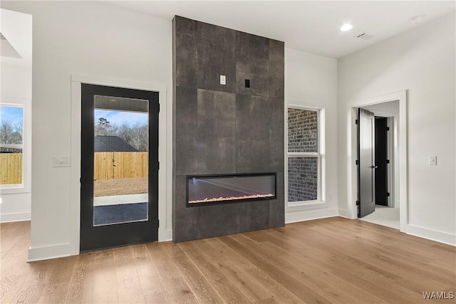 unfurnished living room featuring a large fireplace and light hardwood / wood-style flooring