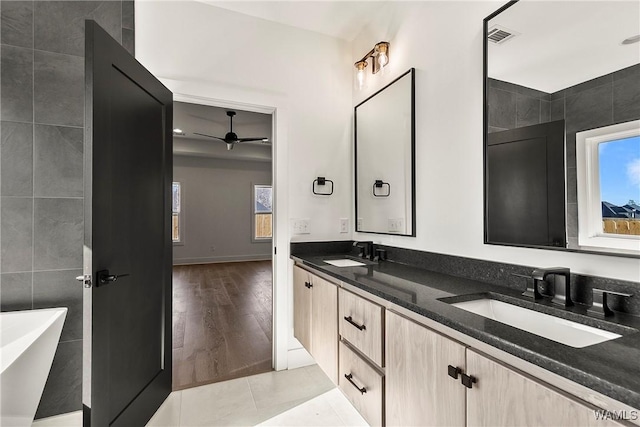 bathroom featuring vanity, a tub, tile walls, and tile patterned floors