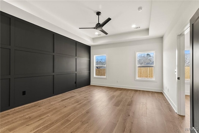 unfurnished bedroom featuring a tray ceiling, light hardwood / wood-style flooring, and ceiling fan