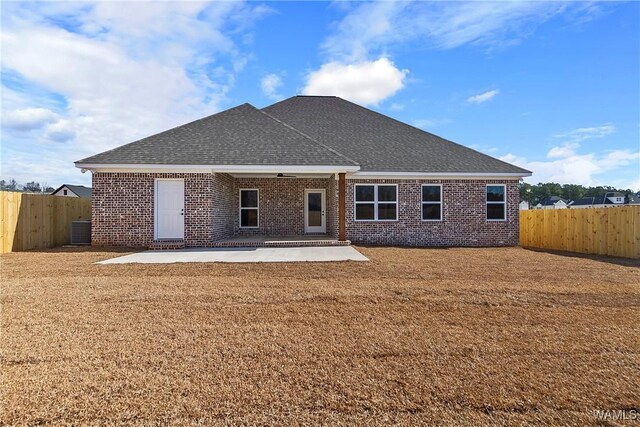 rear view of property with central AC, a patio, and a lawn