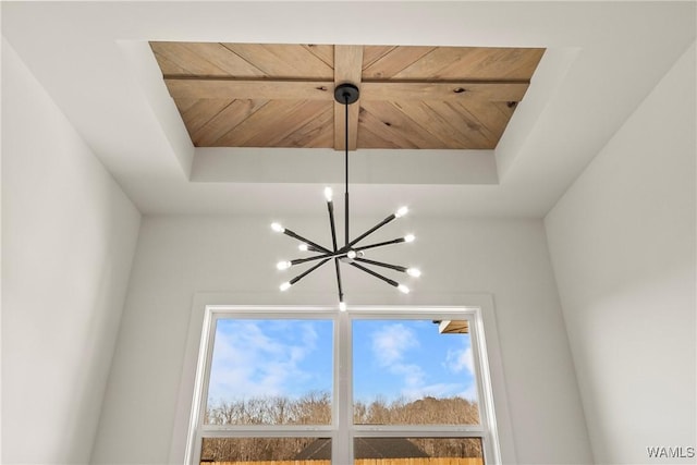 details featuring a notable chandelier, wood ceiling, and a raised ceiling