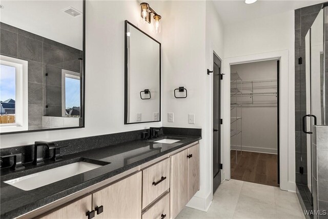 bathroom featuring a shower with door, vanity, and tile patterned floors