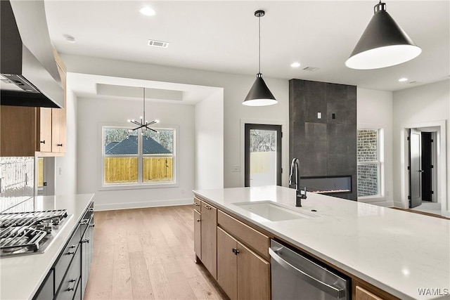 kitchen featuring decorative light fixtures, sink, island exhaust hood, stainless steel appliances, and light wood-type flooring