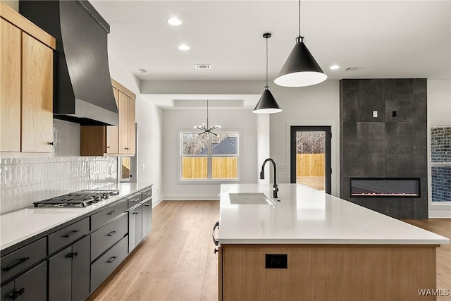 kitchen featuring pendant lighting, sink, an island with sink, and stainless steel gas stovetop