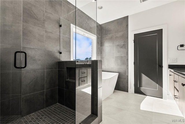 bathroom featuring independent shower and bath, vanity, tile walls, and tile patterned floors