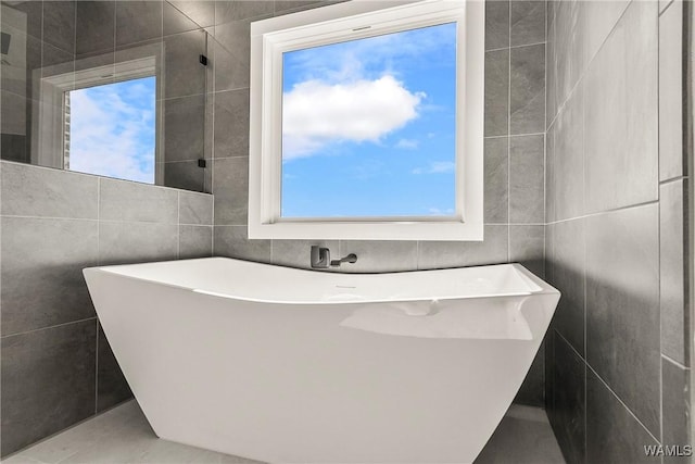 bathroom with a bathing tub and tile walls