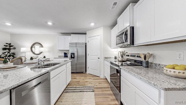 kitchen featuring white cabinets, sink, appliances with stainless steel finishes, and light hardwood / wood-style flooring