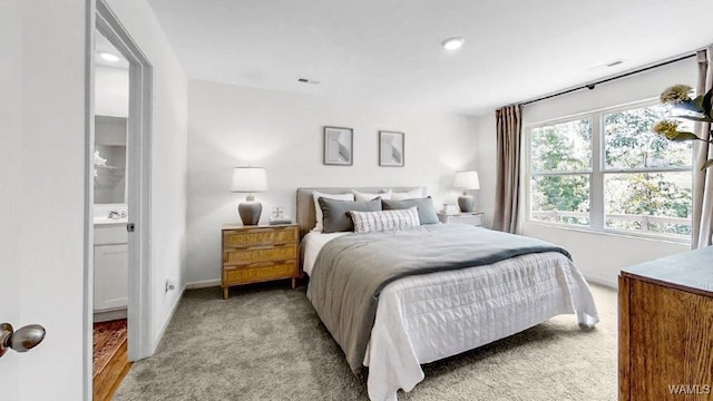 bedroom with connected bathroom and light colored carpet