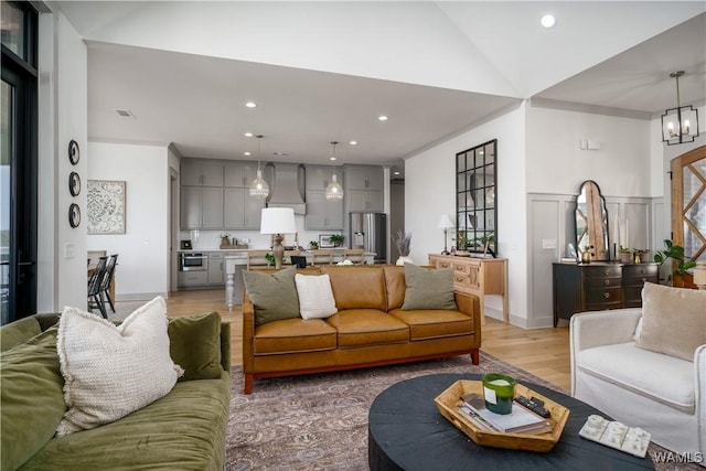 living room with a decorative wall, visible vents, recessed lighting, and light wood-type flooring