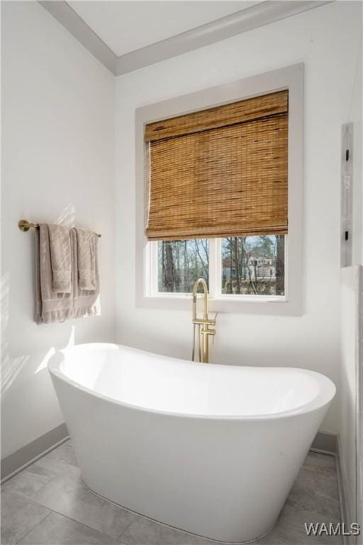 full bath with a freestanding bath and baseboards