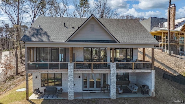 rear view of property with a patio area, a sunroom, and roof with shingles