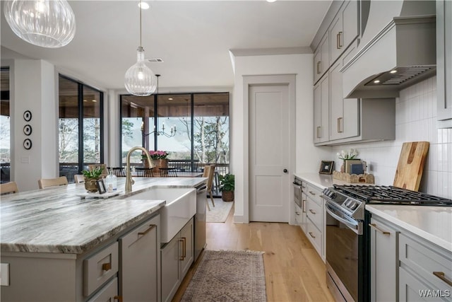 kitchen with gray cabinets, a sink, tasteful backsplash, appliances with stainless steel finishes, and custom exhaust hood