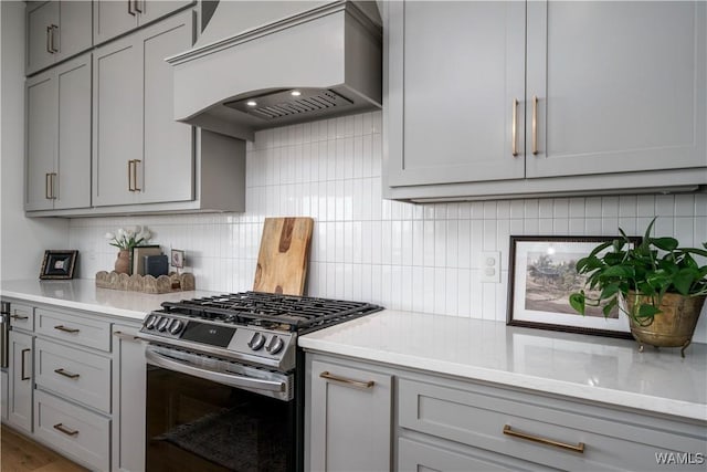 kitchen featuring custom exhaust hood, gray cabinetry, light countertops, and stainless steel gas stove