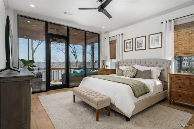 bedroom featuring expansive windows, multiple windows, wood finished floors, and access to outside