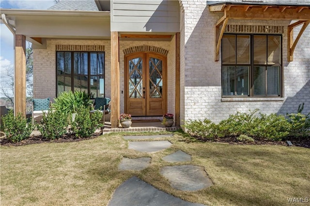 doorway to property featuring brick siding and a yard
