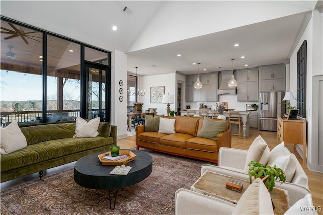 living area featuring recessed lighting, high vaulted ceiling, light wood-type flooring, and baseboards