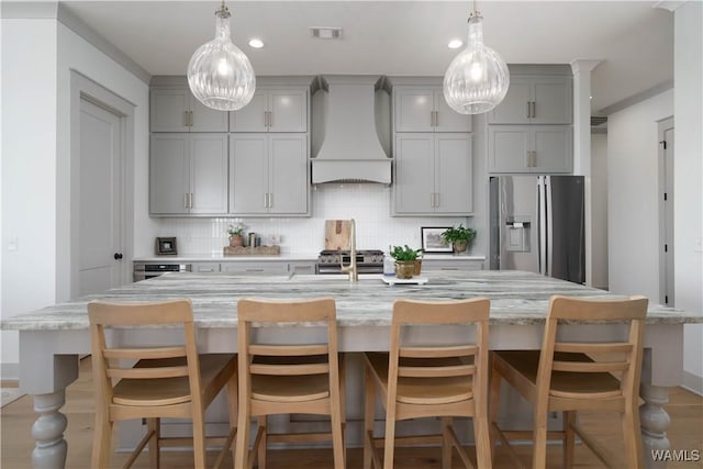 kitchen featuring visible vents, custom exhaust hood, gray cabinetry, decorative backsplash, and stainless steel appliances