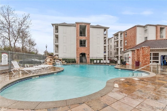 view of swimming pool with pool water feature and a patio area