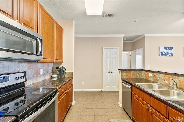 kitchen with crown molding, stainless steel appliances, sink, and dark stone countertops