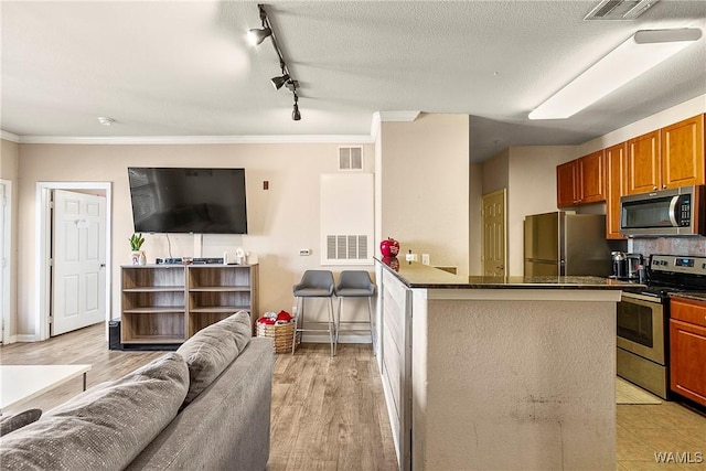 kitchen featuring crown molding, light hardwood / wood-style flooring, stainless steel appliances, and a textured ceiling