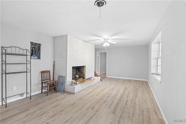 unfurnished living room featuring a brick fireplace, light wood-type flooring, and ceiling fan