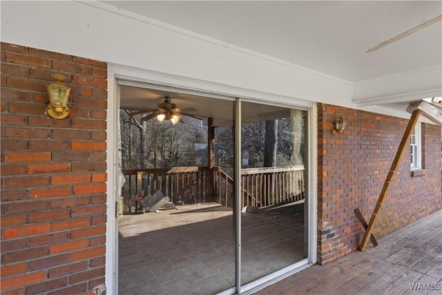 exterior space with ceiling fan and brick wall