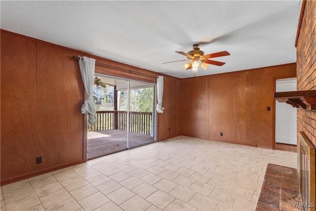 unfurnished living room with ceiling fan, a fireplace, light tile patterned floors, and wood walls