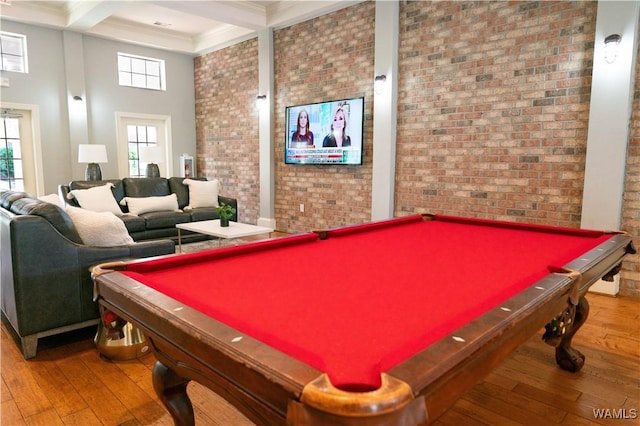 recreation room with a healthy amount of sunlight, brick wall, and wood finished floors