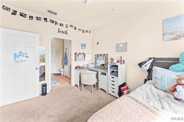 bedroom featuring ensuite bath, visible vents, and light colored carpet