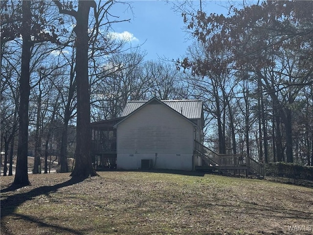 view of side of property featuring metal roof, central AC unit, stairway, and a lawn