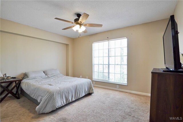 carpeted bedroom with a textured ceiling, a ceiling fan, and baseboards