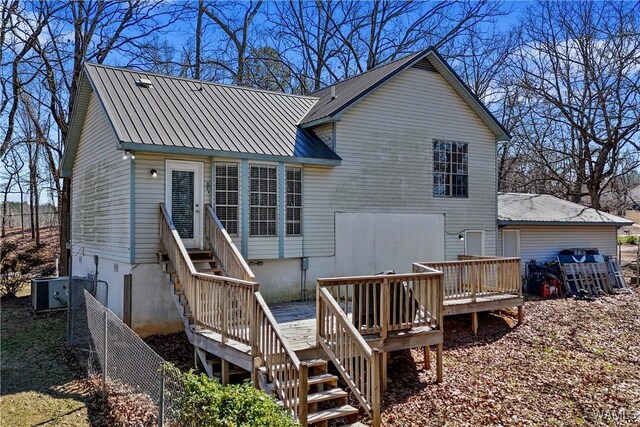 rear view of property featuring metal roof, a wooden deck, and fence