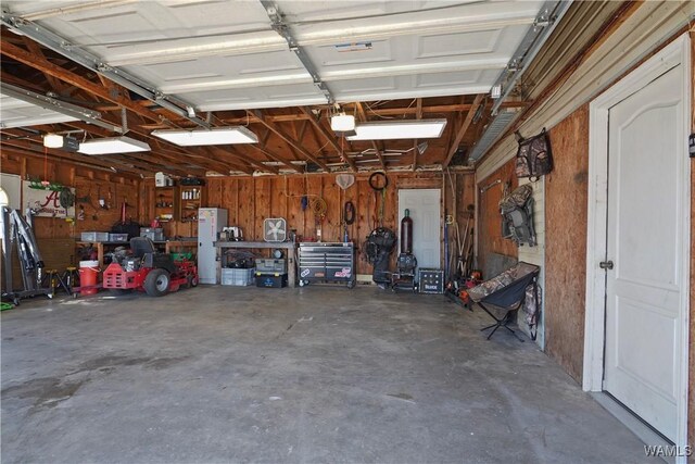 garage with a garage door opener, wooden walls, and a workshop area