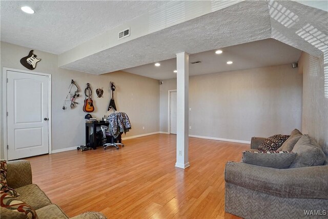 living area featuring baseboards, visible vents, a textured ceiling, light wood-type flooring, and recessed lighting