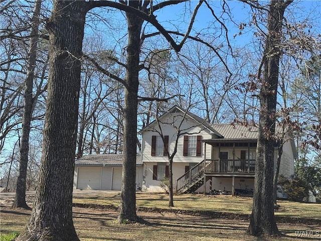 tri-level home featuring an attached garage, stairs, metal roof, and a front yard