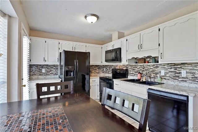 kitchen featuring white cabinets, a sink, backsplash, and black appliances