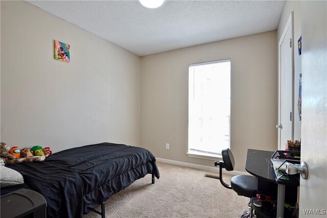 carpeted bedroom featuring a textured ceiling and baseboards