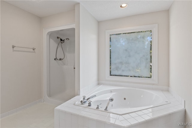 bathroom featuring tiled bath, a healthy amount of sunlight, and a textured ceiling