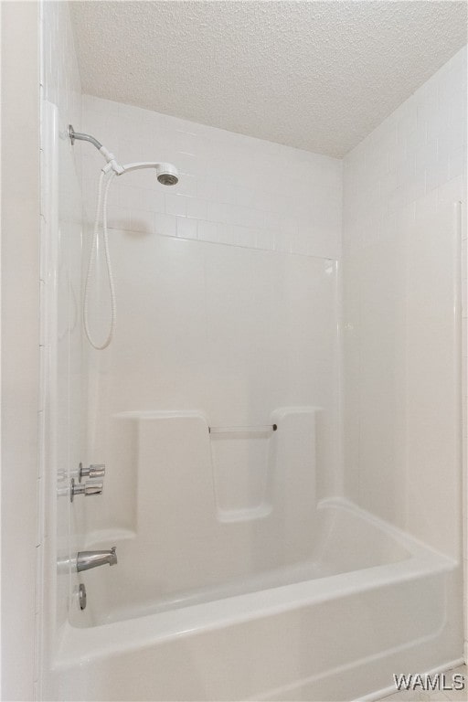 bathroom with shower / tub combination and a textured ceiling