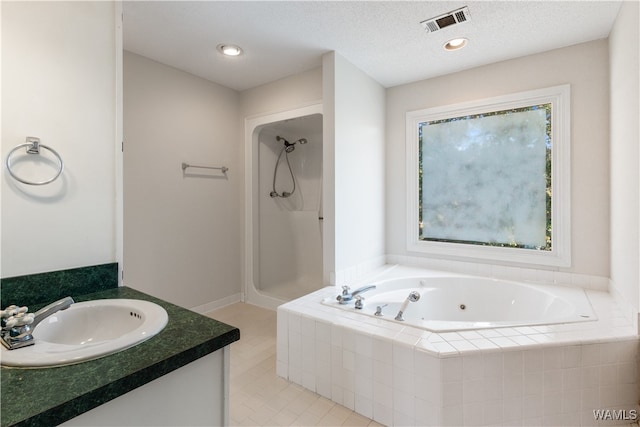 bathroom with tile patterned flooring, vanity, shower with separate bathtub, and a textured ceiling