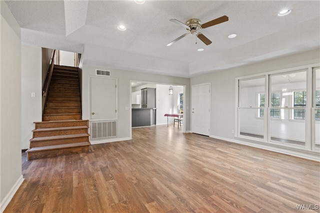 unfurnished living room with ceiling fan, wood-type flooring, and a textured ceiling