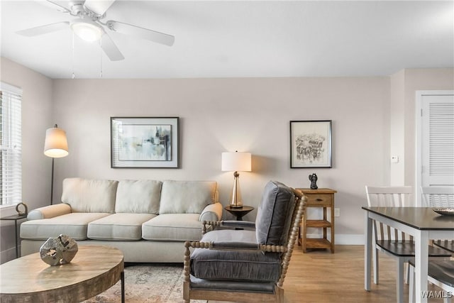 living area with a ceiling fan, light wood-style flooring, and baseboards