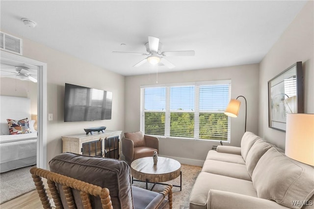 living room featuring baseboards, ceiling fan, visible vents, and wood finished floors